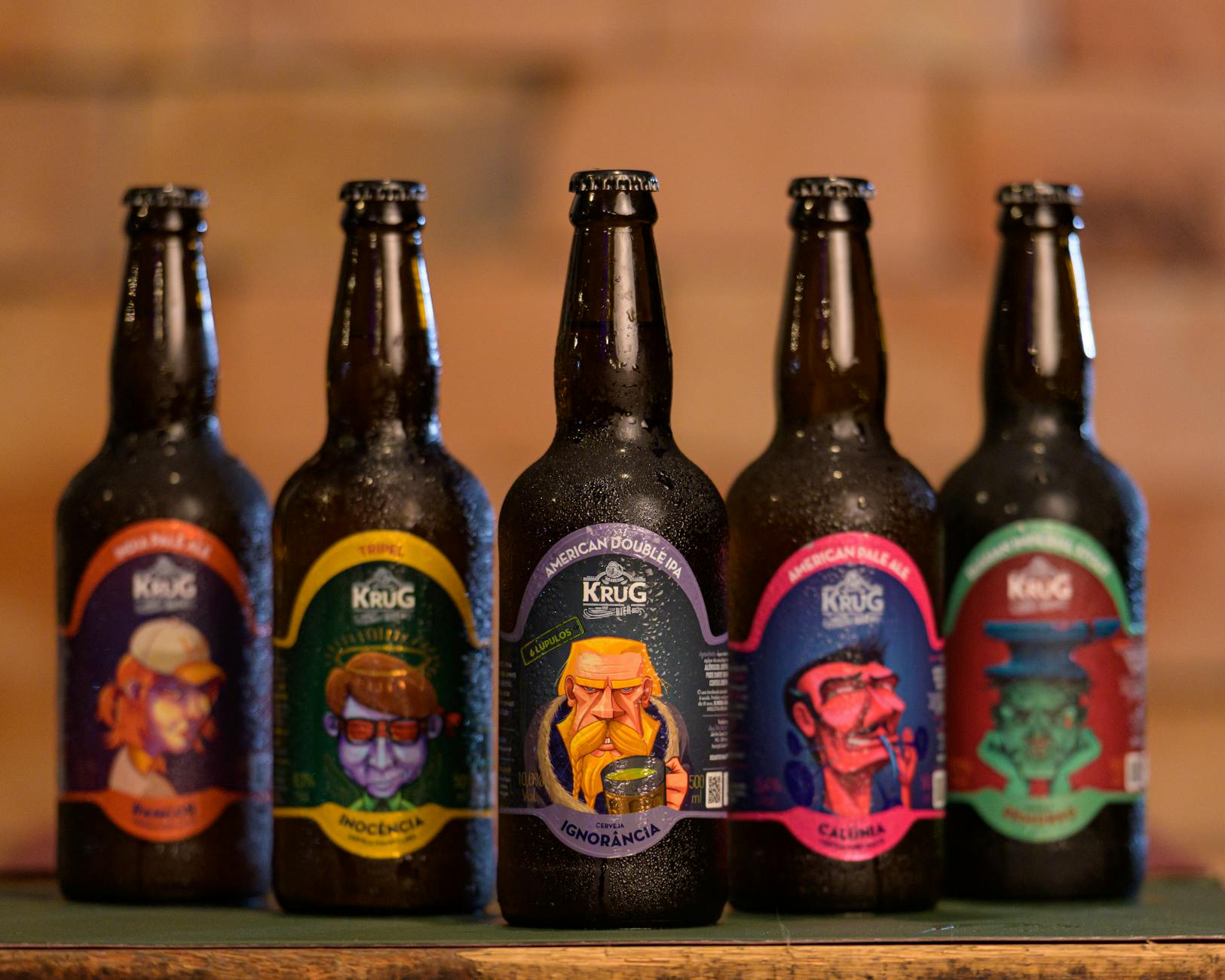 Butelki rzemieślniczego piwa Krug z kolorowymi etykietami na drewnie