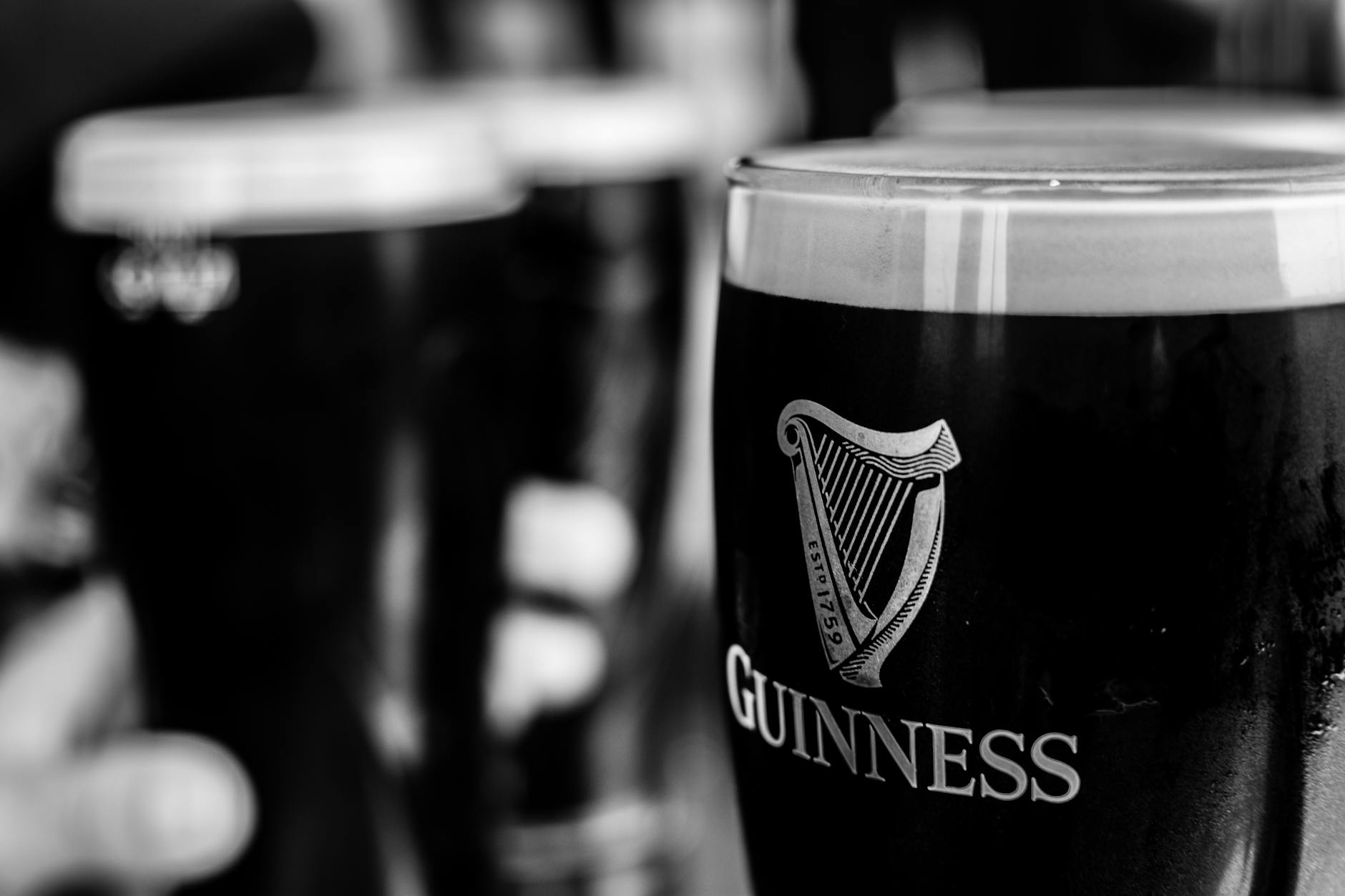 Pinty ciemnego piwa Guinness w irlandzkim pubie, zdjęcie czarno-białe