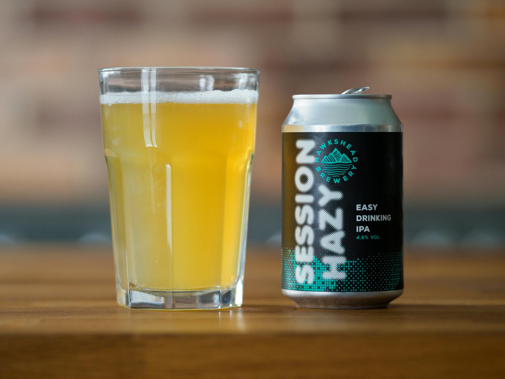 Szklanka i puszka mętnego piwa IPA na drewnianym stole