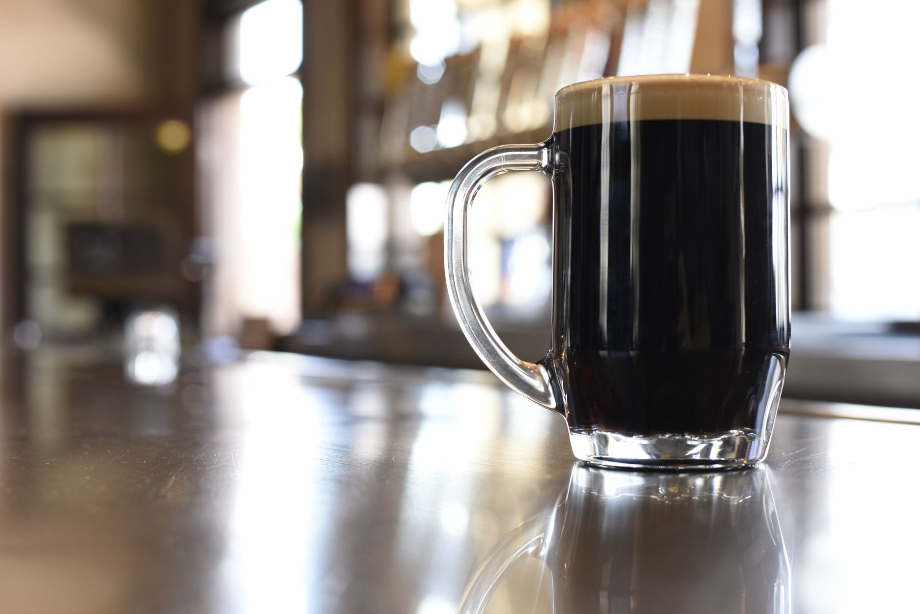 Kufel ciemnego piwa owsianego stout z pianą na barowym blacie